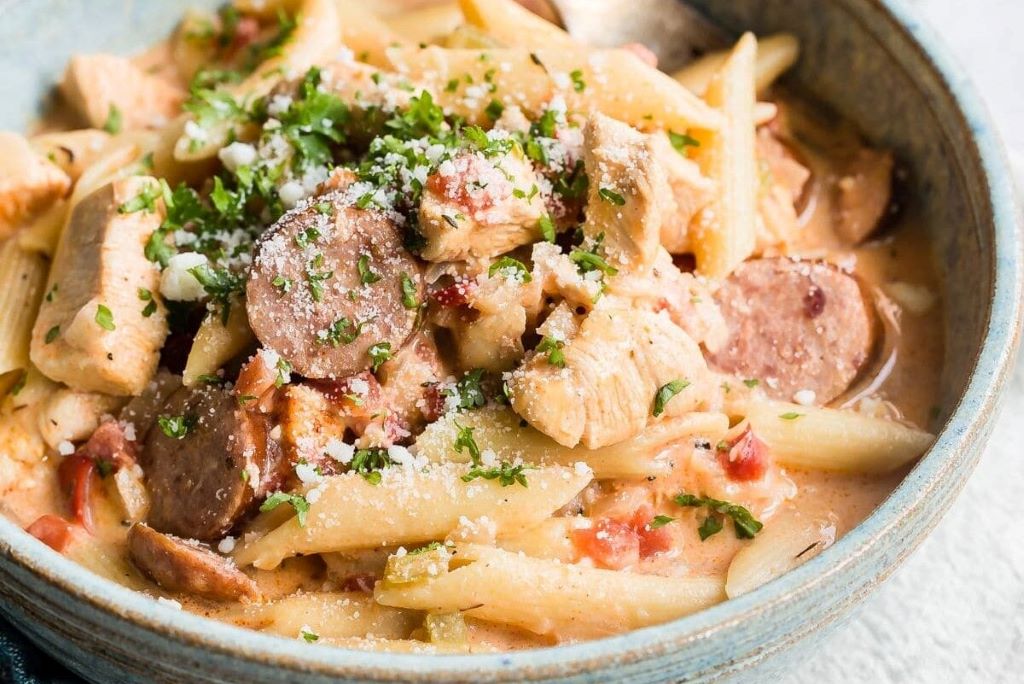 Bowl of creamy Cajun Alfredo sauce with pasta, garnished with parsley and sprinkled with Cajun seasoning