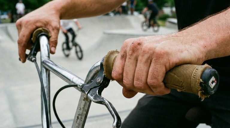 Close-up of a rider holding ribbed BMX grips on handlebars.